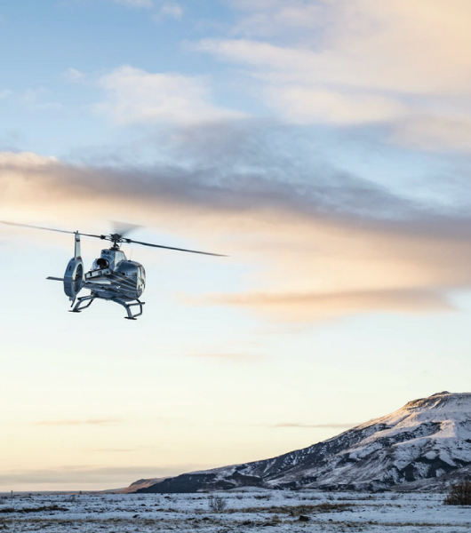 Helicopter flies over snow covered tundra